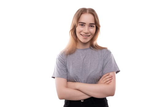 Kind modest bright blond teenager girl with braces in a gray T-shirt.