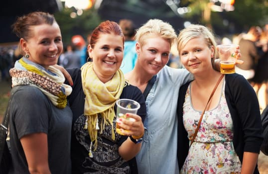 Portrait of group of women at music festival with beer, smile and hug in nature together. Drink, celebration and friends relax at outdoor party with freedom, adventure and happy people at concert