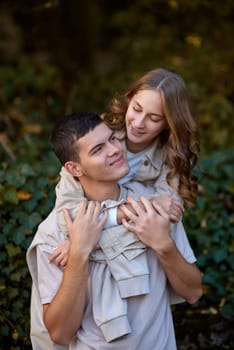 Young Cute Female Hugs Boyfriend. In Autumn Outdoor. Lovers Walking in Park. Attractive Funny Couple. Lovestory in Forest. Man and Woman. Cute Lovers in the Park. Family Concept. Happy Couple.