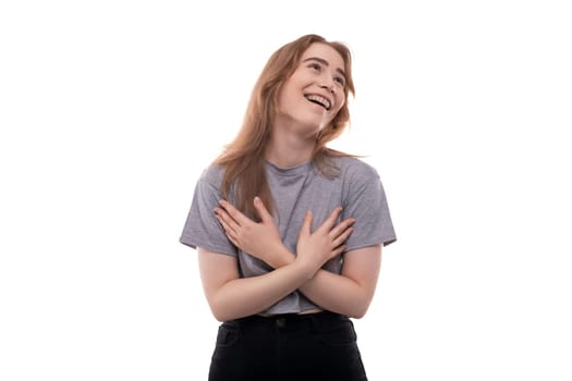 Teenage girl with blond hair in a gray T-shirt laughs on a white background