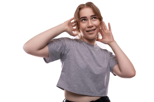 Teenage girl posing in a gray T-shirt on a white background with copy space.