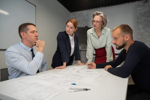 Designers engineers at a meeting discuss working drawings