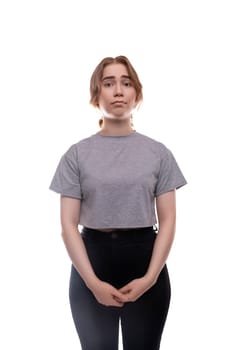 Tired Caucasian fair-haired teenage girl in a gray T-shirt close-up.