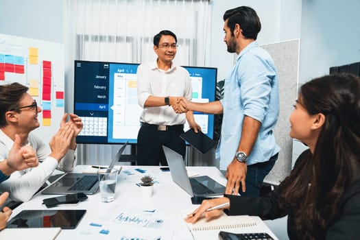 Happy office worker and project manager shake hand in meeting room after successfully achieving business task on time and on schedule. Project management tracking software for business success.Prudent