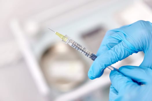 Physician hand in blue gloves with syringe for injection