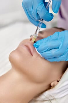 cosmetologist makes injections to enlarge the lips of beautiful woman. procedure lip augmentation