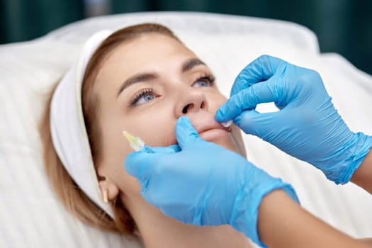 cosmetologist makes injections to enlarge the lips of beautiful woman. beauty injections.
