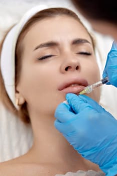 cosmetologist makes injections to enlarge the lips of beautiful woman. procedure lip augmentation