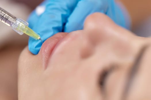 cosmetologist makes injections to enlarge the lips of beautiful woman. procedure lip augmentation
