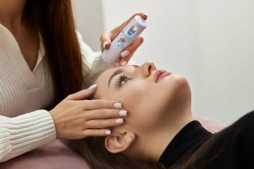 cosmetologist using primer spray for eyelash extension procedure in salon