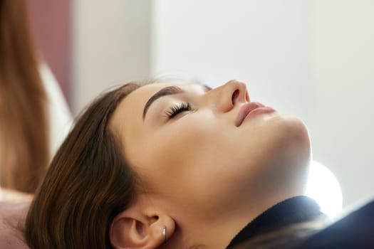 cosmetologist using primer spray for eyelash extension procedure in salon