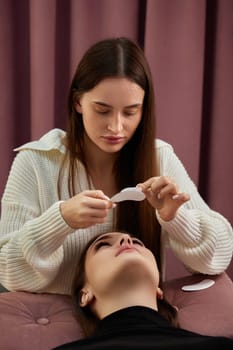 cosmetologist preparing glue ribbon under eye. Eyelash extension procedure