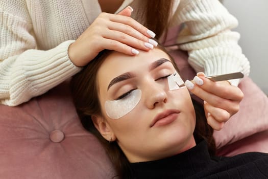 cosmetologist removes glue cotton tape under eye. Eyelash extension procedure
