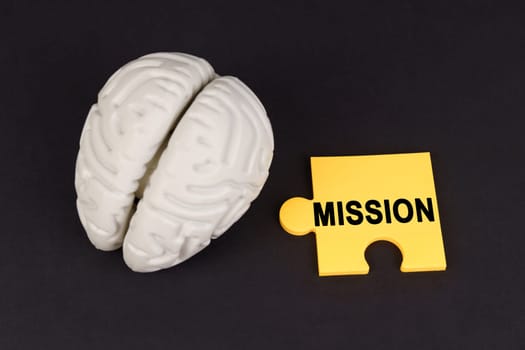 On a black surface lies a brain and a yellow puzzle with the inscription - Mission. Education and science concept.