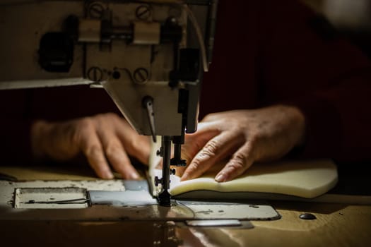 Sewing machine and men's hands of a tailor needle in focus