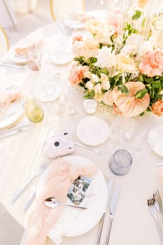 Fujifilm Instax mini instant camera lies on a set table next to plates and photographs. High quality photo
