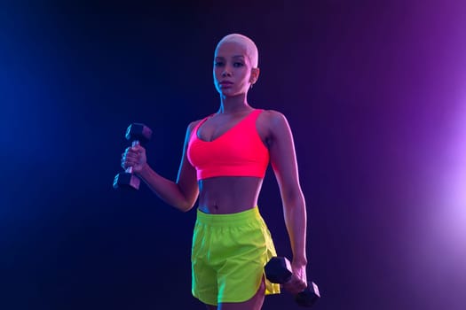 Sporty fit woman, athlete with dumbbells make fitness exercises on black background. Download cover for music collection for fitness classes. Sports recreation. Beautiful black young woman
