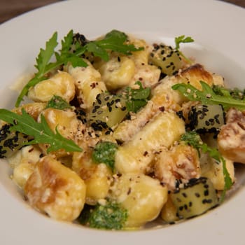 RECIPE FOR POTATO GNOCCHI WITH ROCKET SALAD PESTO AND CREAMY PARMESAN SAUCE. High quality photo