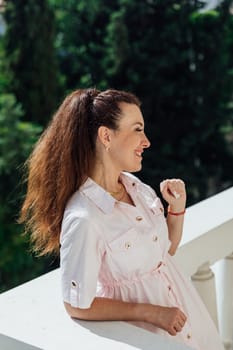 woman in summer light dress on balcony looking at the street