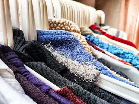 Hangers with a variety of clothes on white rack. Home storage of clothes. Clutter. Littery. Declutter. Garage sale
