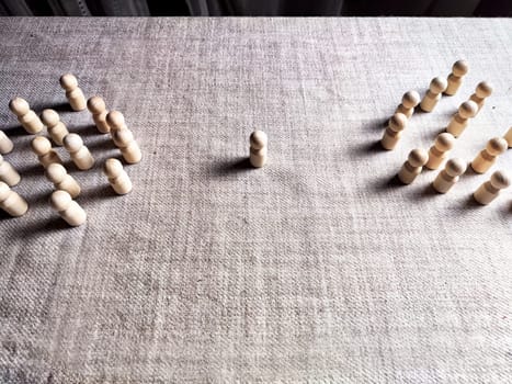 Wooden toy in the center and two groups of other figures. The pressure of groups and the collective on the individual. Bowling. Leadership and teamwork