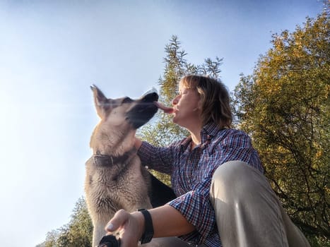 Adult girl with shepherd dog taking selfies in forest. Middle aged woman and big shepherd dog on nature. Friendship, love, communication, fun, hugs