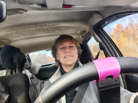 Portrait of female driver in solo journey. Adult mature woman holding steering wheel and looking through windscreen in travel by vehicle on vacation. Lady girl who is owner or rent car for travel