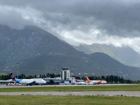 Planes stand at the airport at the foot of the mountains in the fog. High quality photo