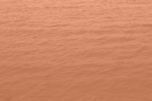 Peach Fuzz toned sea water texture. Pool water with sun reflections. Trendy colour 2024 year. High quality photo