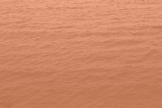 Peach Fuzz toned sea water texture. Pool water with sun reflections. Trendy colour 2024 year. High quality photo
