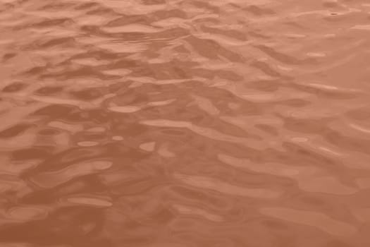 Peach Fuzz toned sea water texture. Pool water with sun reflections. Trendy colour 2024 year. High quality photo