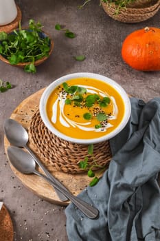 Delicious homemade creamy pumpkin soup with cream with sesame seeds and watercress.