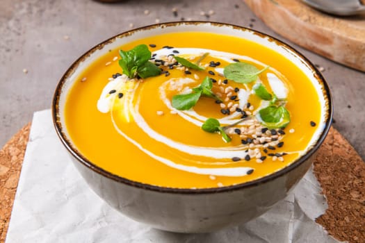 Delicious homemade creamy pumpkin soup with cream with sesame seeds and watercress.