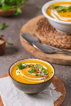 Delicious homemade creamy pumpkin soup with cream with sesame seeds and watercress.