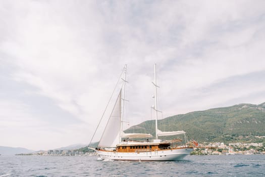Luxury sailing yacht sails on the sea against the backdrop of green mountains. High quality photo