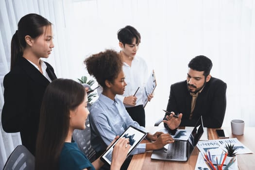 Multiracial analyst team use BI Fintech software to analyze financial data on meeting table. Financial dashboard data display on laptop screen with analyzed chart for marketing indication. Concord