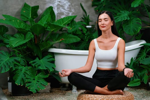 Young woman doing morning yoga and meditation in natural garden with plant leaf, enjoying the solitude and practicing meditative poses. Mindfulness activity and healthy mind lifestyle. Blithe