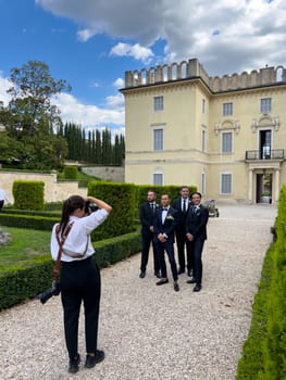 Photographer girl shoots the groom with his friends in the garden of an old mansion. High quality photo