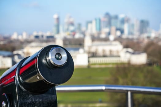 Lookout telescope monocular with blurred Canary Wharf district in London at distance