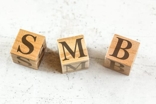 Three wooden cubes with letters SMB (stands for Small to medium Business) on white board.