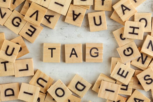 Top down view, pile of square wooden blocks with word TAG on white board. 