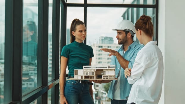 Skilled engineer holds house model and explain about house construction to skilled manager. Group of interior designer inspect architectural model. Working together, Civil engineering. Tracery