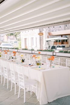 Bouquets of flowers stand on a festive long table under a canopy near the house. High quality photo