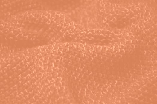 Peach fuzz colour monochrome texture knitted fabric. Peach knitted Jersey as textile background. Monochrome color background. Wool knitting texture. Trendy color 2024. High quality photo