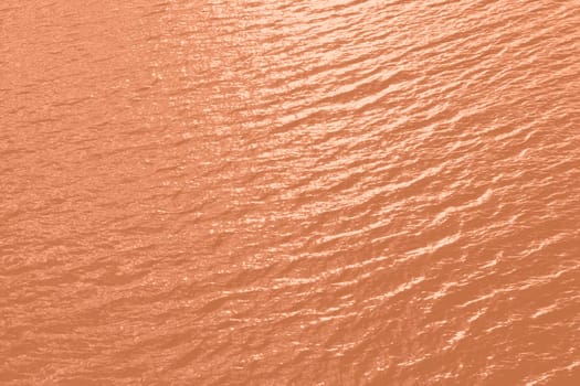 Peach Fuzz toned sea water texture. Pool water with sun reflections. Trendy colour 2024 year. High quality photo