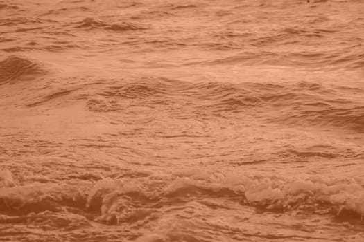 Peach Fuzz toned sea water texture. Pool water with sun reflections. Trendy colour 2024 year. High quality photo