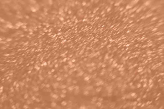 Peach Fuzz color glitter background. Blurred monochrome background with bokeh. Blurred glitters shimmering dust macro close up. High quality photo