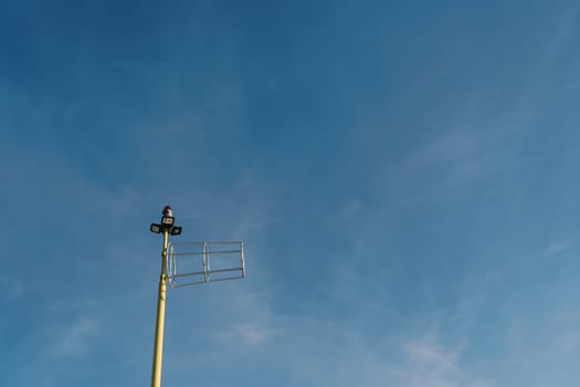 Antenna on a pole with searchlights and a signal lantern on the top against the sky. High quality photo