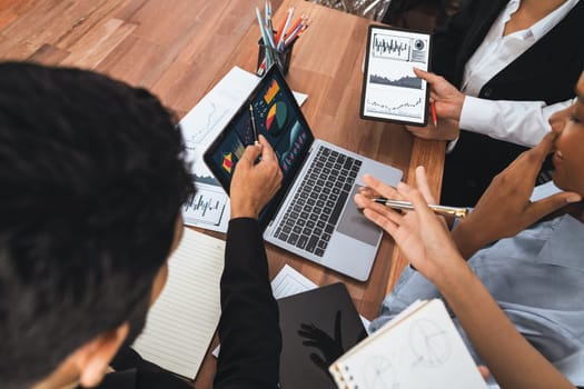 Multiracial analyst team use BI Fintech software to analyze financial data on meeting table. Financial dashboard data display on laptop screen with analyzed chart for marketing indication. Concord