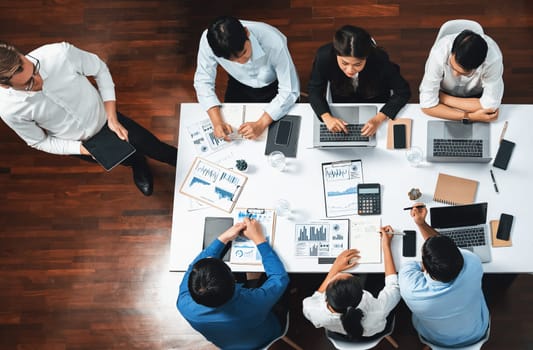 Top view analyst team utilizing BI Fintech to analyze financial data at table in meeting room. Analytic BI dashboard power on paper for business insight and strategic marketing planning. Prudent